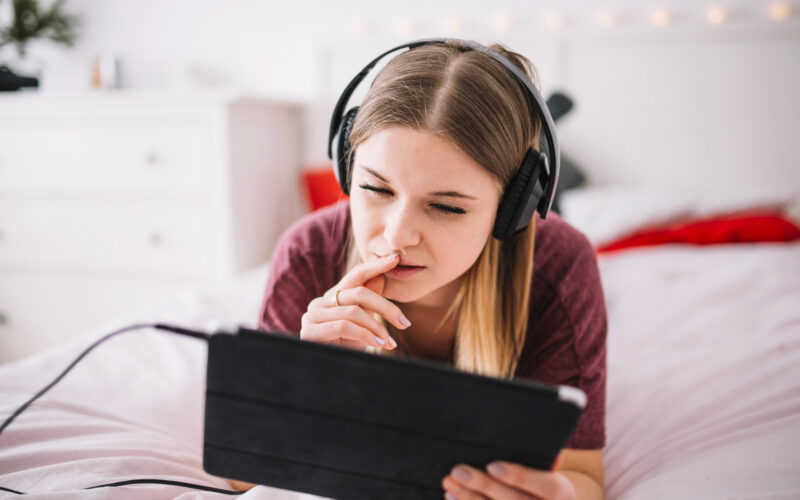 o tanara cu casti pe urechi foloseste o tableta