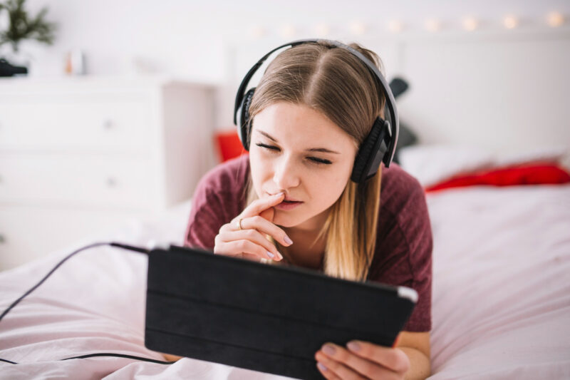 o tanara cu casti pe urechi foloseste o tableta