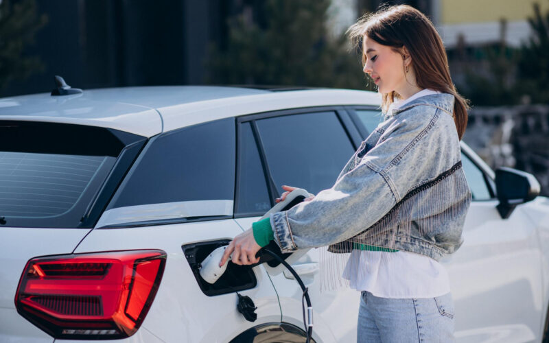 o femeie isi conecteaza masina electrica la o statie de incarcare