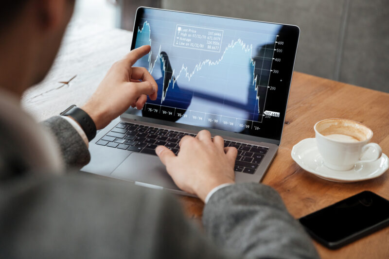 un investitor priveste un grafic pe ecranul unui laptop