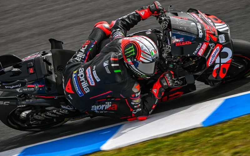 pilot motogp fotografiat inclinat extrem pe partea dreapta pe ciruit de mare viteza