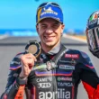 pilot motogp cu casca in mana pe pista de cirucit cu medalia in mana