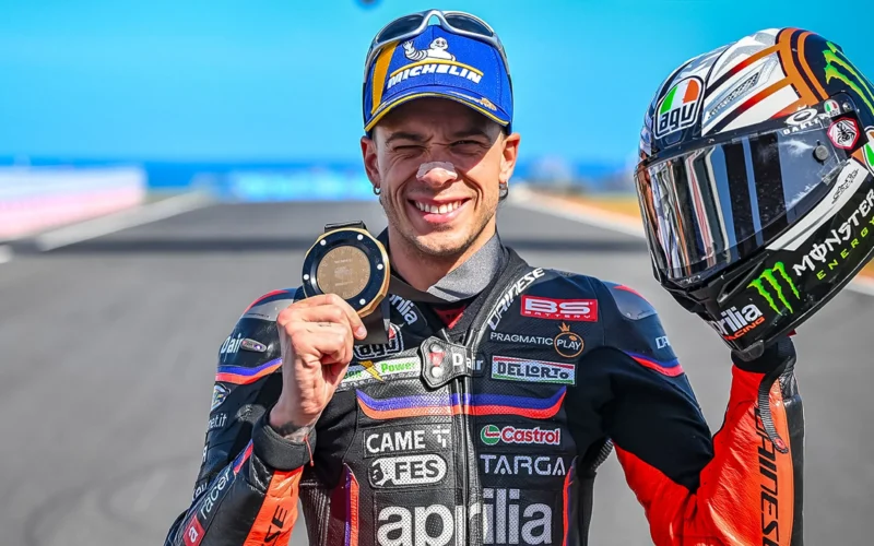pilot motogp cu casca in mana pe pista de cirucit cu medalia in mana