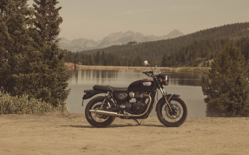 motocicleta clasica de culoare neagra la marginea unui lac montan