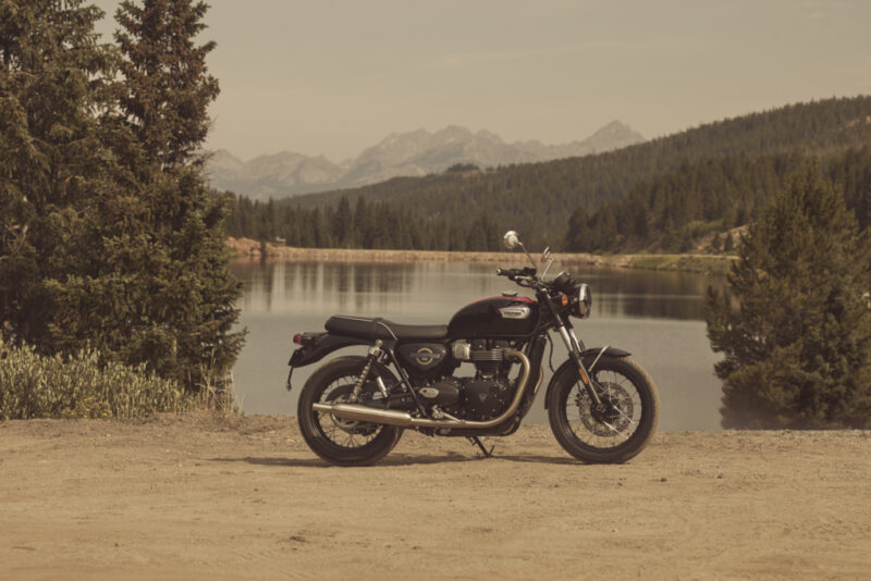 motocicleta clasica de culoare neagra la marginea unui lac montan