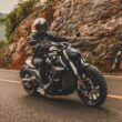 motociclceta de tip cruiser de culoare neagra surprinsa pe un drum de munte cu stanci in fundal