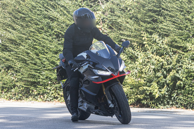 motocicleta super sport de culoare neagra pe strada cu copaci in spate