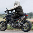 motocicleta ducati neagra surprinsa pe strada la marginea unui camp