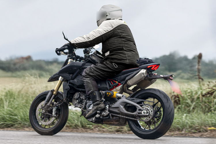 motocicleta ducati neagra surprinsa pe strada la marginea unui camp