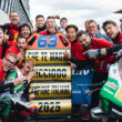 grup de persoane ce se bucura de castigarea uui premiu pe un circuit moto