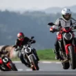 trei motociclete naked pe un drum virajat cu un munte in fundal