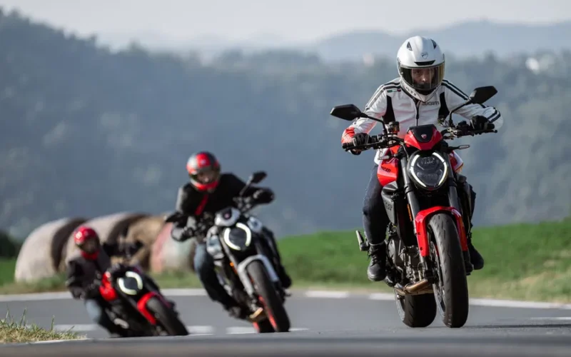 trei motociclete naked pe un drum virajat cu un munte in fundal