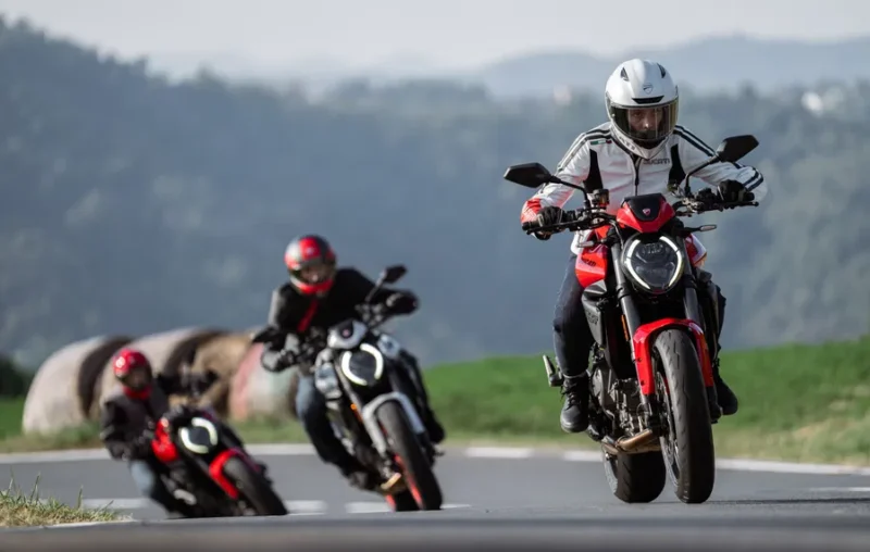 trei motociclete naked pe un drum virajat cu un munte in fundal