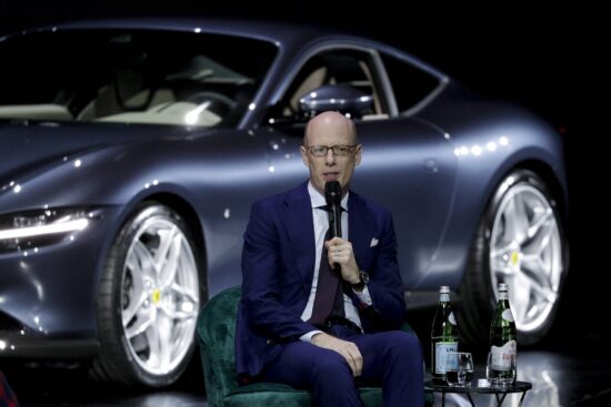Michael Leiters, posibilul nou CEO Porsche, vorbind la un microfon cu un model Ferrari pe fundal