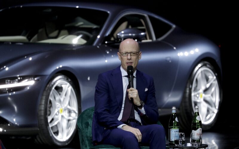Michael Leiters, posibilul nou CEO Porsche, vorbind la un microfon cu un model Ferrari pe fundal