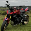 motocicleta rosie honda fotografiata pe un camp