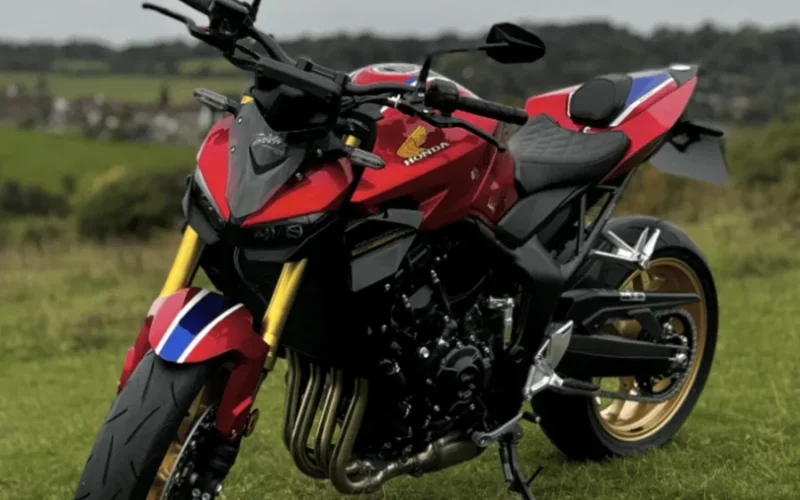 motocicleta rosie honda fotografiata pe un camp