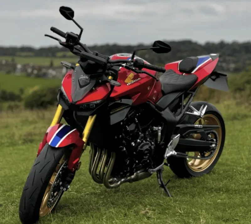 motocicleta rosie honda fotografiata pe un camp