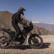motocicleta neagra enduro fotografiata pe teren accidentat cu un munte in fundal