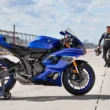 motocicleta super sport de culoare albastra pe circuit cu rider in fundal