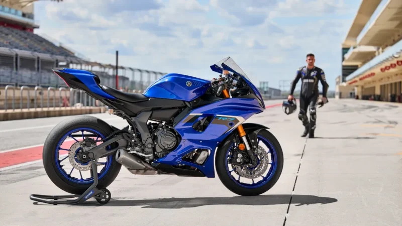 motocicleta super sport de culoare albastra pe circuit cu rider in fundal