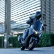 scuter yamaha negru in fata unei cladirri de sticla