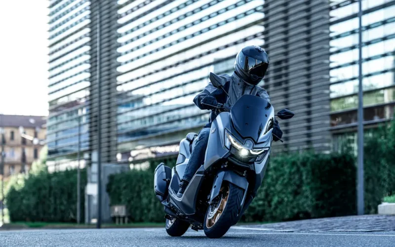 scuter yamaha negru in fata unei cladirri de sticla