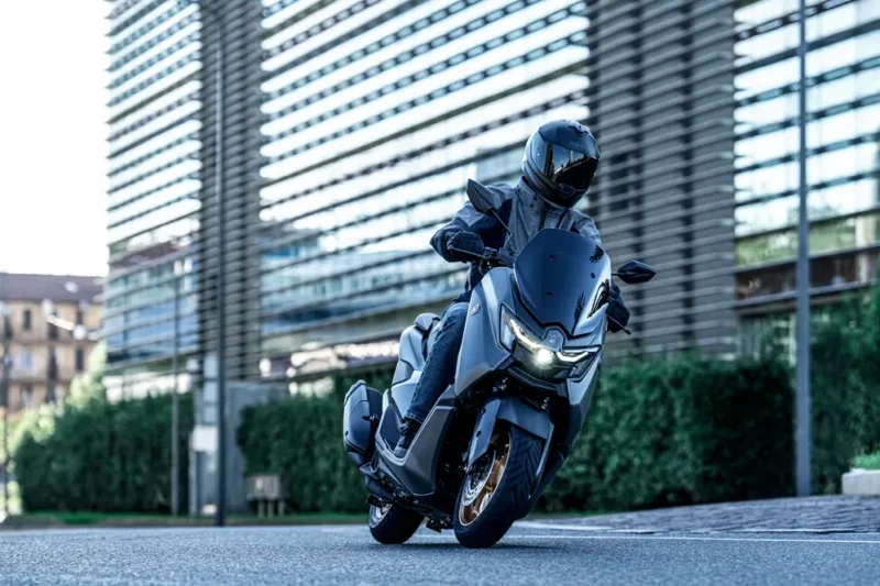 scuter yamaha negru in fata unei cladirri de sticla