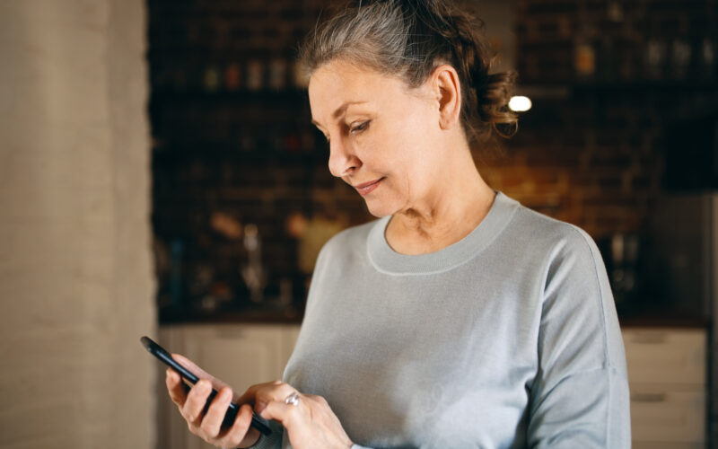 o femeie mai in varsta foloseste un telefon