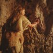 Copil neanderthalian care desenează pe pereții unei peșteri