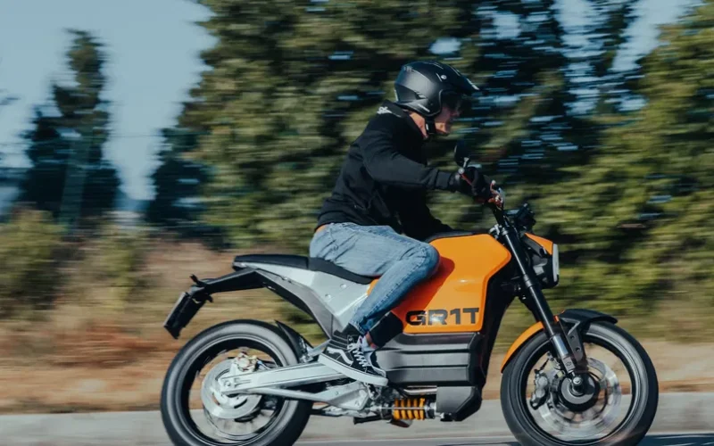 motocicleta galbena electrica cu o padure in fundal