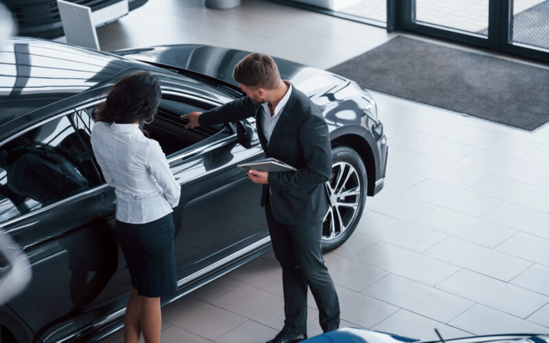 un dealer auto de lux ii prezinta o masina unei cliente