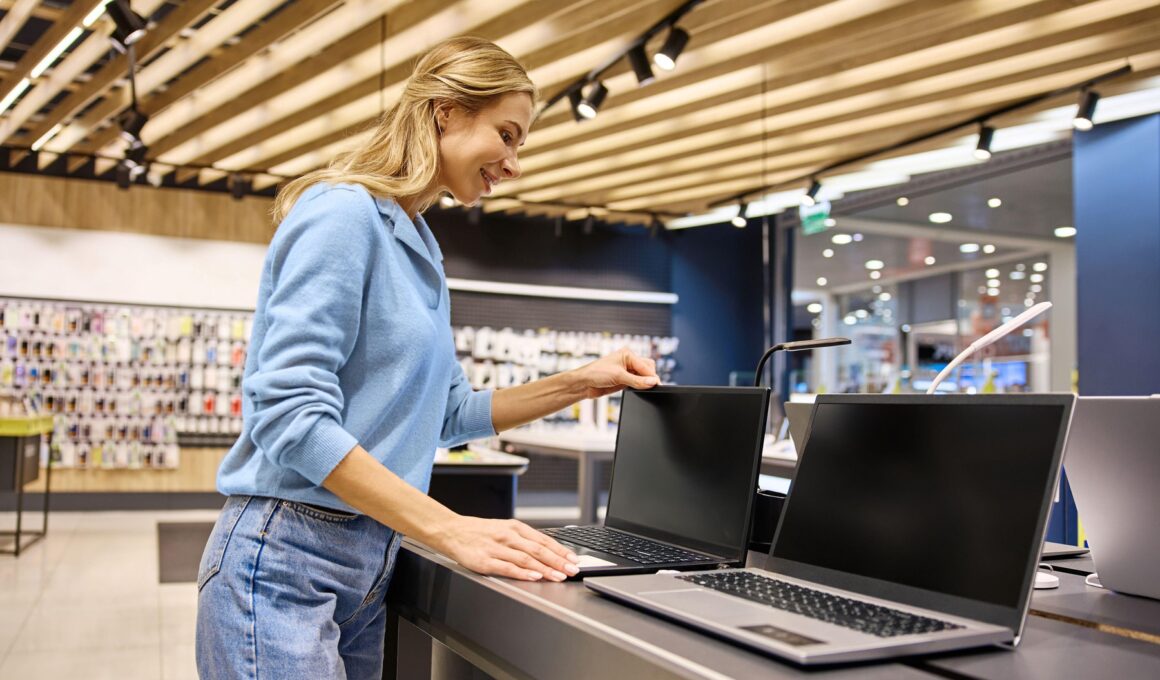 o femeie se uita la laptopuri intr-un magazin de electronice