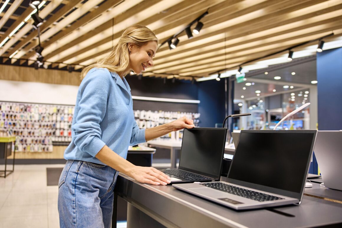 o femeie se uita la laptopuri intr-un magazin de electronice