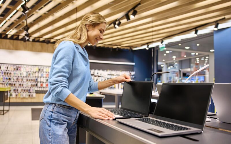 o femeie se uita la laptopuri intr-un magazin de electronice